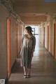 A woman standing in a long hallway in a building.