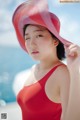 A woman in a red bathing suit and a pink hat.