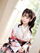 A woman in a kimono sitting on a window sill.