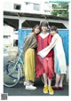 A group of three women standing next to each other near a bike.