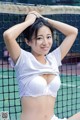 A woman in a white shirt is posing on a tennis court.