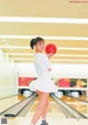 A woman holding a red bowling ball in a bowling alley.