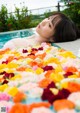 A woman laying in a pool covered in flowers.