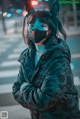 A woman wearing a cat ears mask standing in the middle of a street.