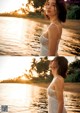 A woman in a white dress standing by the water.