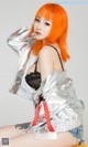 A woman with orange hair wearing a silver jacket.