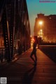 A woman standing on a bridge at night. 