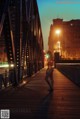 A person walking across a bridge at night. 