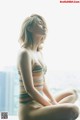 A woman sitting on a window sill in a bathing suit.