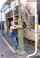 A woman leaning against a green pole on the side of a street.