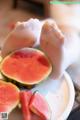 A person holding a slice of watermelon on a plate.