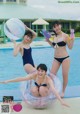 A group of young women in bikinis standing next to a swimming pool.