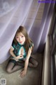 A woman sitting on the floor in front of a window.