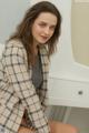 A woman sitting on top of a white dresser next to a mirror.