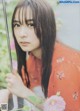 A woman in an orange kimono holding an umbrella.