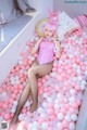 A woman in a pink bunny costume sitting in a bathtub filled with pink and white balloons.