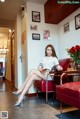 A woman sitting on a red chair reading a book.