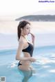 A woman in a black bathing suit standing in a pool.