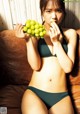 A woman in a bikini holding a bunch of grapes.