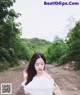 A woman in a white dress standing on a dirt road.