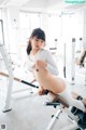 A naked woman is sitting on a bench in a gym.