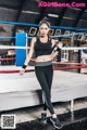 A woman in a black top and black leggings standing in a boxing ring.