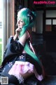 A woman with green hair sitting on a window sill.