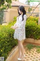 A woman in a white dress standing in a flower garden.