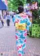 A woman in a blue and pink kimono walking down a street.