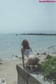 A woman sitting on a concrete wall by the ocean.