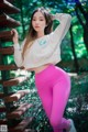 A woman in a white sweatshirt and pink leggings posing for a picture.