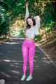 A woman in a white top and pink leggings posing for a picture.