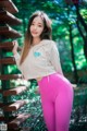 A woman in pink leggings leaning against a wooden staircase.