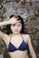 A woman in a blue bikini laying in the water.