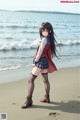 A girl standing on a beach next to the ocean.