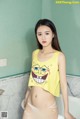 A woman in a yellow top and white panties posing in a bathtub.