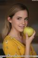 A young woman holding a green apple in her hand.