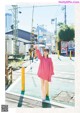 A woman in a pink dress standing on a street corner.