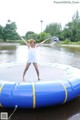 A woman standing on a trampoline in the middle of a lake.