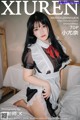 A woman in a maid outfit sitting on a bed.