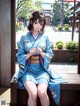 A woman in a blue kimono sitting on a bench.