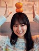 A woman holding two oranges on top of her head.