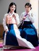 A couple of women in hanbok sitting next to each other.