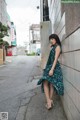 A woman leaning against a wall on the side of a street.